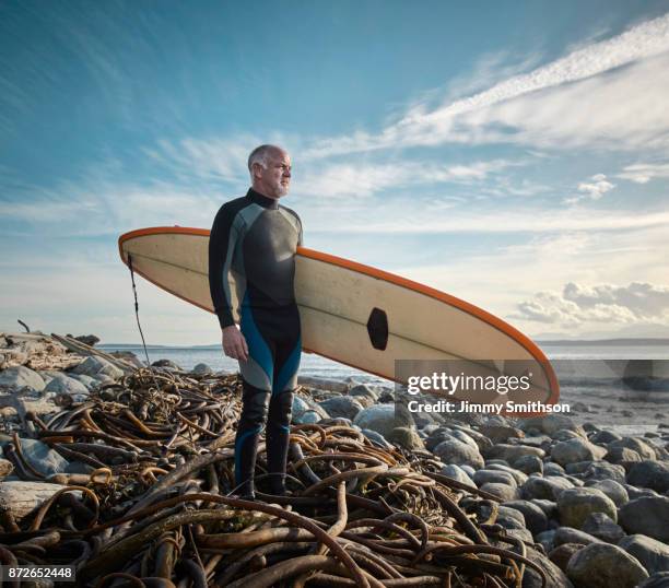 surfer holding surfboard. - north pacific stock pictures, royalty-free photos & images