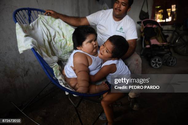 Mario Gonzales looks as his elder son, Mario hugs his ten-month-old brother Luis at their home in Tecoman, Colima state, Mexico on November 8, 2017....