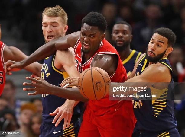 Bobby Portis of the Chicago Bulls battles for a loose ball with Domantas Sabonis and Cory Joseph of the Indiana Pacers at the United Center on...