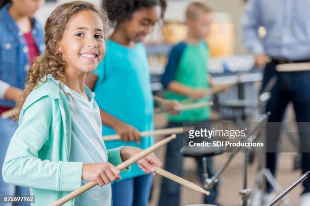 meisje wordt onderbroken vanaf drummen klasse om te glimlachen voor camera - drum stockfoto's en -beelden