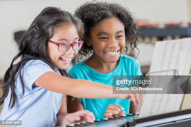 little girl turns page during piano duet with friend - kid conductor stock pictures, royalty-free photos & images