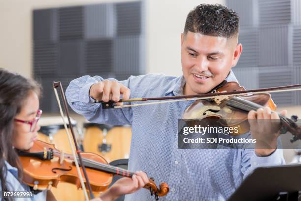 mid adult male violin teacher plays a piece with young student - kid conductor stock pictures, royalty-free photos & images