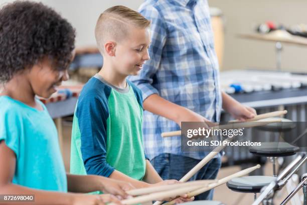 joven practica tambores con profesor y compañero de clase - instrumentos de percusión fotografías e imágenes de stock