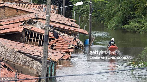 Two residents row a canoe past destroyed houses in a street flooded by the Mearim river in Bacabal, in the state of Maranhao, northern Brazil, on May...