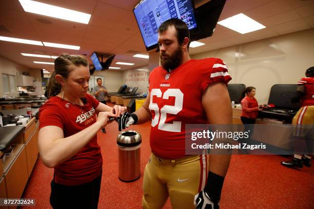 Assistant Head Athletic Trainer Laura Schnettgoecke of the San Francisco 49ers tapes of Erik Magnuson in the locker room prior to the game against...