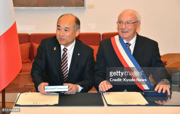 Masaomi Tokuta , mayor of Sagara, Kumamoto Prefecture in southwestern Japan, and Pierre Rousseau, mayor of Saint-Valentin, central France, attend a...