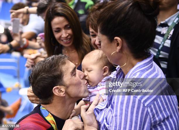 S Michael Phelps kisses his son Boomer next to his partner Nicole Johnson after he won the Men's 200m Butterfly Final during the swimming event at...