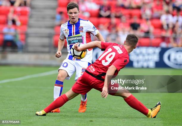 Benjamin Garuccio of Adelaide gets away with a handball in front of Wayne Brown of Newcastle during the round six A-League match between Adelaide...