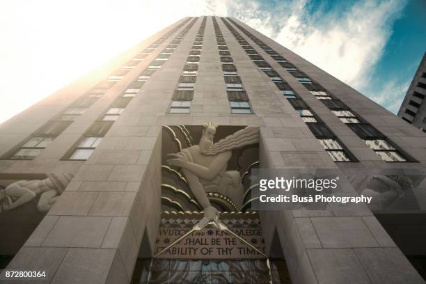 view from below of 30 rockefeller plaza, surrounded by other buildings comprising the rockefeller center, in midtown manhattan, new york city - 30 rockefeller plaza stock pictures, royalty-free photos & images