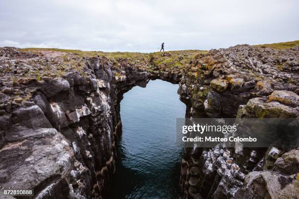 man on top of natural rocky arch, snaefellsnes, iceland - island holiday stock-fotos und bilder
