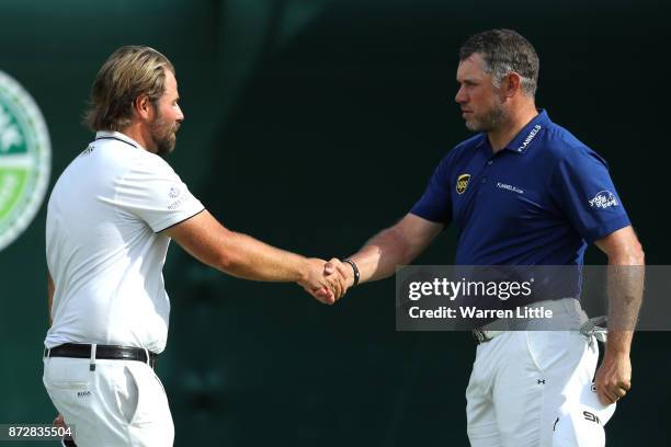 Lee Westwood of England shakes hands with Victor Dubuisson of France on the 18th green dduring the third round of the Nedbank Golf Challenge at Gary...