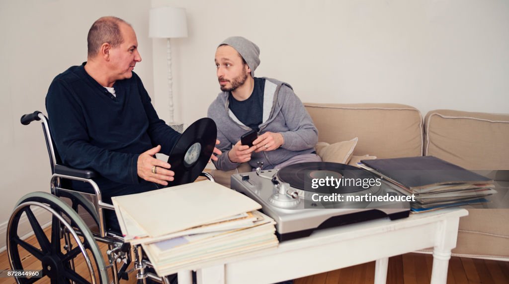 Man visiting a temporary disabled friend enjoying vintage records.