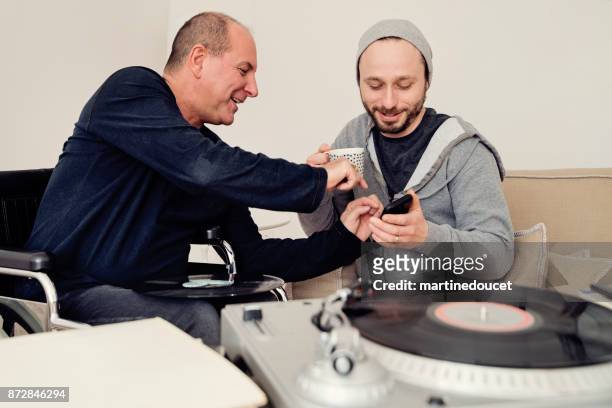man visiting a temporary disabled friend enjoying vintage records. - disability collection stock pictures, royalty-free photos & images