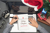 usiness woman hand writing Merry Christmas and Happy New Year 2017 text on note book. concept office christmas and happy new year.