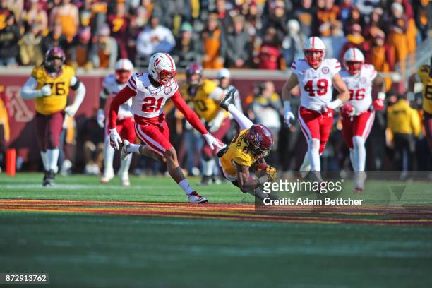 Tyler Johnson of the Minnesota Golden Gophers trips while carrying the ball in the second quarter against the Nebraska Cornhuskers at TCF Bank...