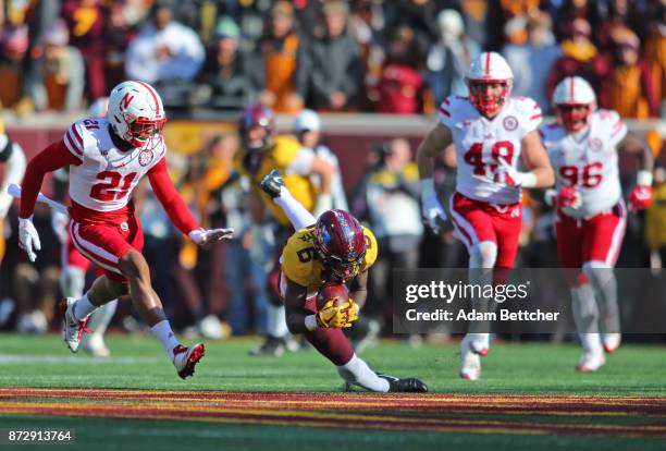 Tyler Johnson of the Minnesota Golden Gophers trips while carrying the ball in the second quarter against the Nebraska Cornhuskers at TCF Bank...