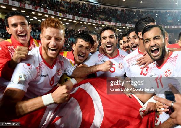 Players of the Tunisian national football team celebrate with their national flag after qualifying for the 2018 World Cup finals after drawing their...