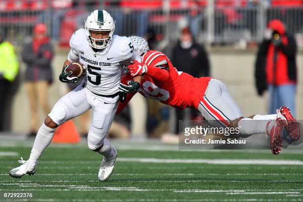 Hunter Rison of the Michigan State Spartans shakes off the tackle from Malik Harrison of the Ohio State Buckeyes in the fourth quarter to pick up...