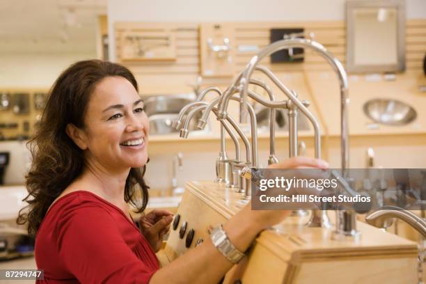 native american woman looking at faucets in plumbing showroom - plumbing showroom stock pictures, royalty-free photos & images