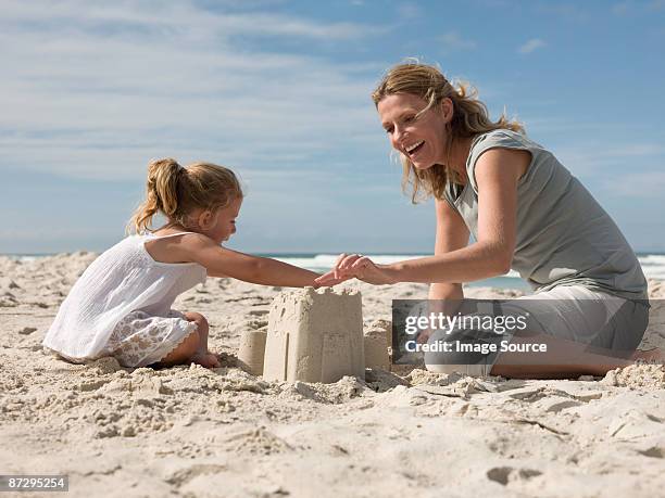 mother and daughter making sandcastles - château de sable photos et images de collection