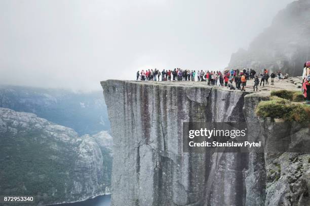 tourists on giant rock formation, fjord, preikestolen - preikestolen norway stock pictures, royalty-free photos & images