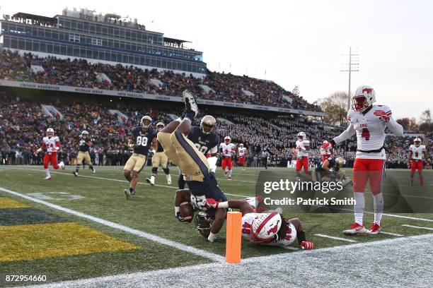 Running back Josh Brown of the Navy Midshipmen is tackled by Anthony Rhone of the Southern Methodist Mustangs in the first quarter at Navy-Marines...