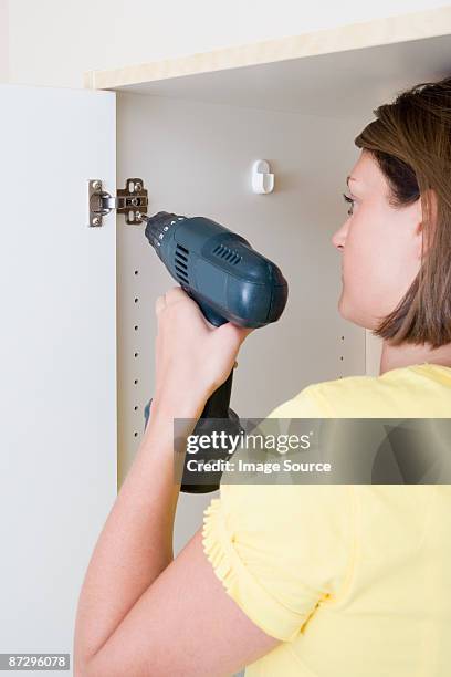 a young woman screwing a wardrobe door to a hinge - hinge stock pictures, royalty-free photos & images