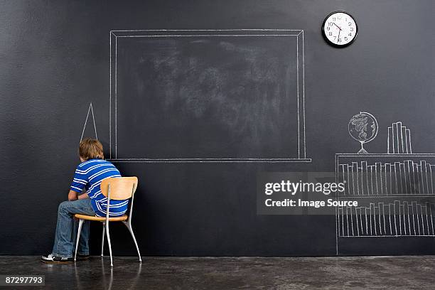 a boy sat in a corner with a chalk dunce cap - dunce cap stock pictures, royalty-free photos & images