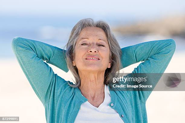 senior woman with hands behind her head - hände hinter dem kopf stock-fotos und bilder