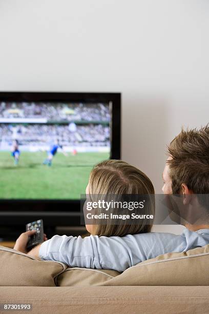 rear view of a couple watching tv - vertical tv stock pictures, royalty-free photos & images