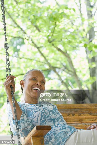 a senior woman sat on a swing seat - hollywoodschaukel stock-fotos und bilder