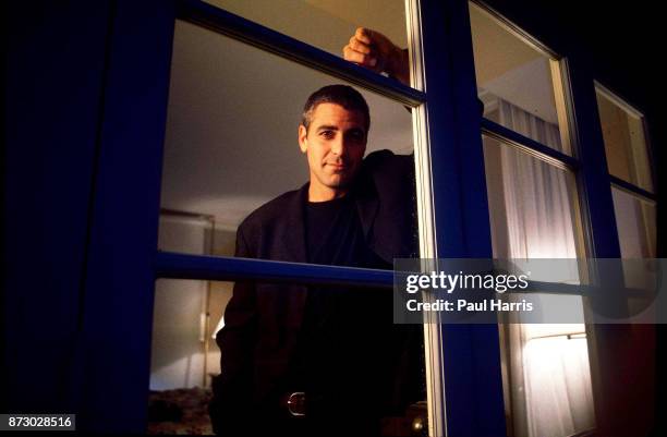 George Clooney during a press conference at the Four Seasons Hotel in Beverly Hills poses in a hotel room looking through a window April 21 Beverly...