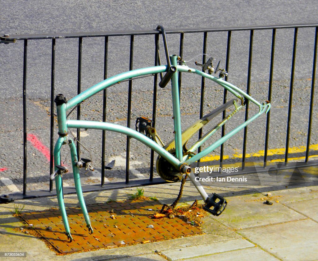 Vandalized bicycle frame chained to a railing - logos removed