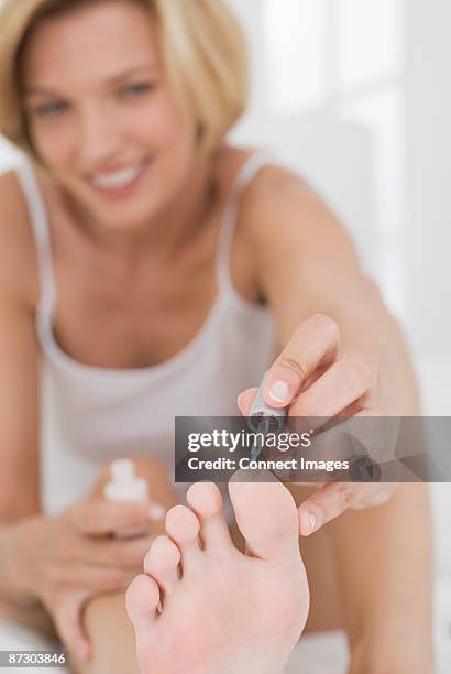a woman applying nail polish to her toenails - toenail painting stock pictures, royalty-free photos & images