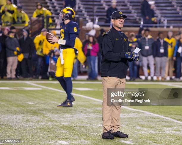 Head coach Jim Harbaugh of the Michigan Wolverines walks around on the field in warm ups before a college football game against the Minnesota Golden...