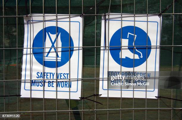 safety vest must be worn and foot protection must be worn signs on the fence around a construction site - stiefel-mit-stahlkappen stock-fotos und bilder