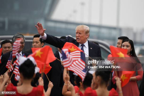 President Donald Trump waves as young girls wave US and Vietnamese national flags before boarding Air Force One to depart to the Philippines, at the...