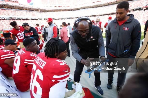 Linebackers Coach Johnny Holland of the San Francisco 49ers talks with Jaquiski Tartt and Reuben Foster on the sideline during the game against the...