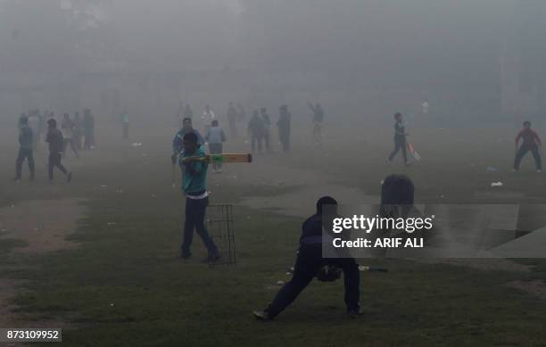 Pakistani youths play cricket amid heavy smog in Lahore on November 12, 2017. Large swathes of Pakistan and north India see a spike in pollution at...