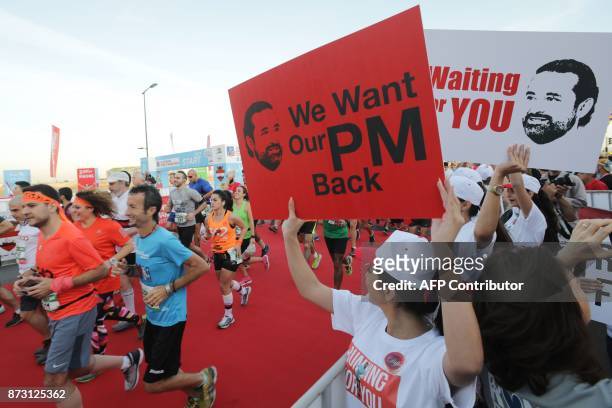 Supporters of Lebanon's resigned prime minister Saad Hariri hold up placards demanding his return from Saudi Arabia on the starting line of Beirut's...