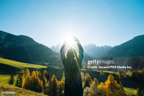 woman reaches for the sun overlooking valley and mountains - series debut stock pictures, royalty-free photos & images