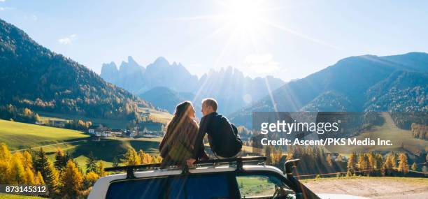 couple sit on car rooftop looking at mountains in the distance - car top view photos et images de collection
