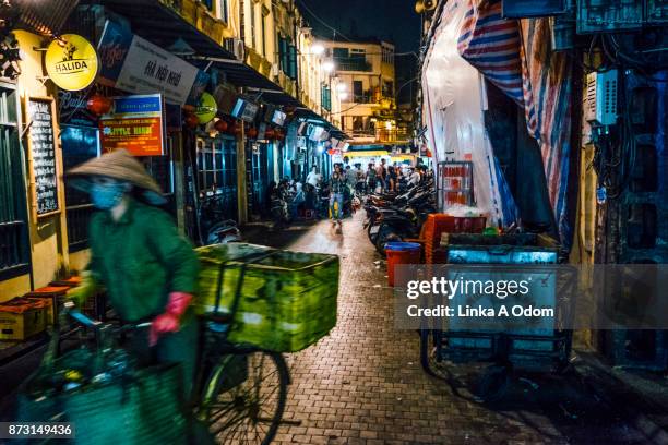 a person riding a bike through hanoi's old quarter. - hanoi fotografías e imágenes de stock
