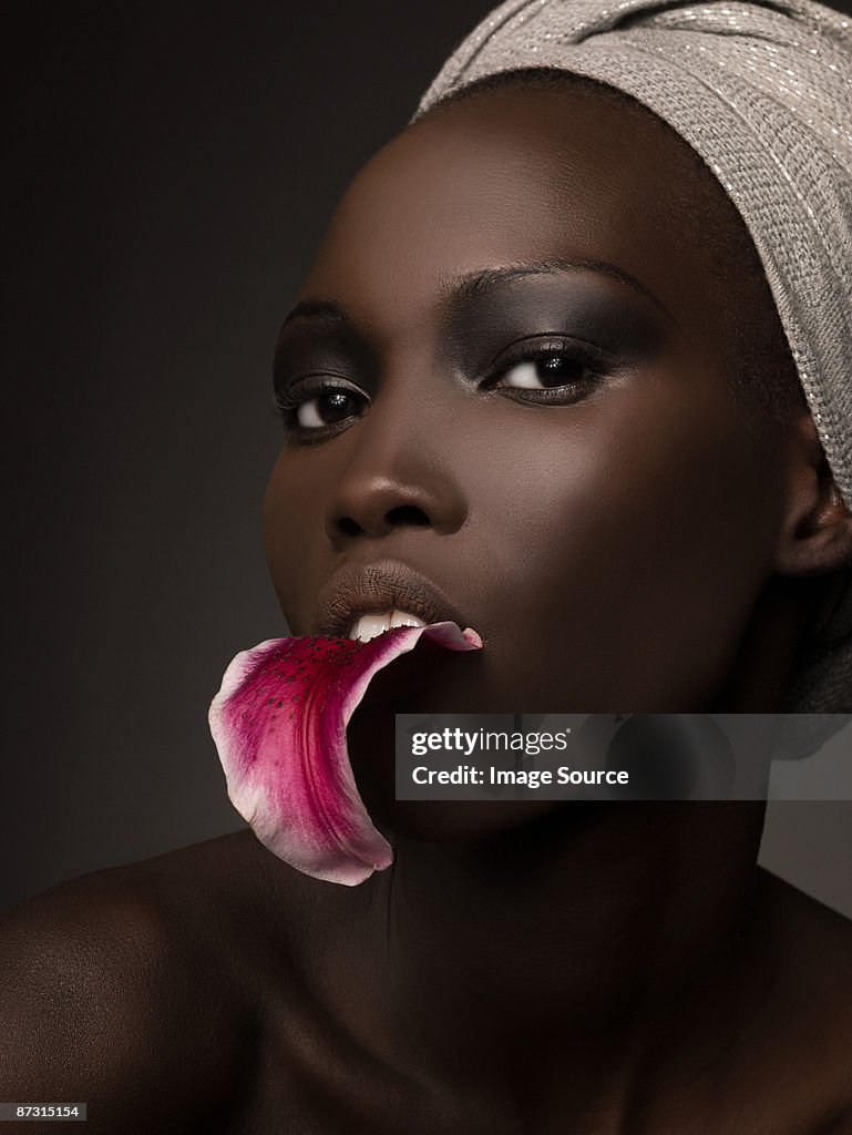 Young woman with petal in her mouth