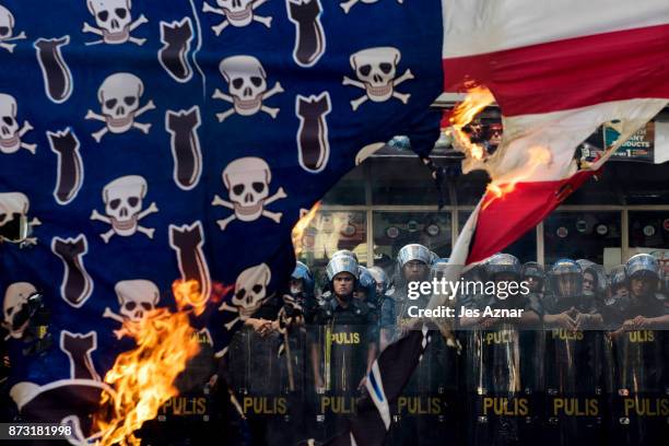 Protesters burn an Amercian flag as they march in the streets of Manila on the day of US President Trump's arrival on November 12, 2017 in Manila,...