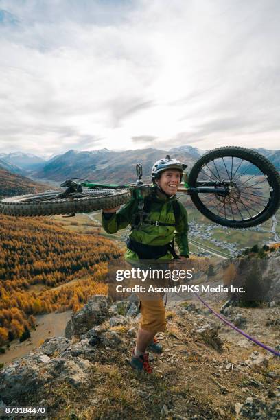 mountain biker ascends mountainous ridge using rope - livigno stock-fotos und bilder