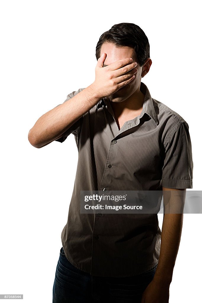 Young man covering his eyes