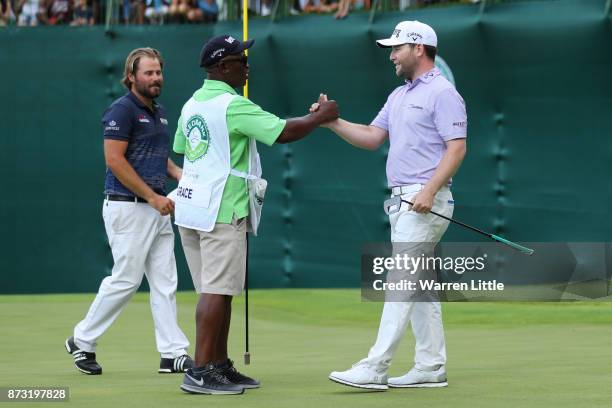 Branden Grace of South Africa shakes hands with caddie Zak Rasego on the 18th green after his victory during the final round of the Nedbank Golf...