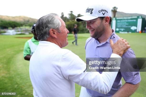 Branden Grace of South Africa is congratulated by Gary Player on the 18th green during the final round of the Nedbank Golf Challenge at Gary Player...