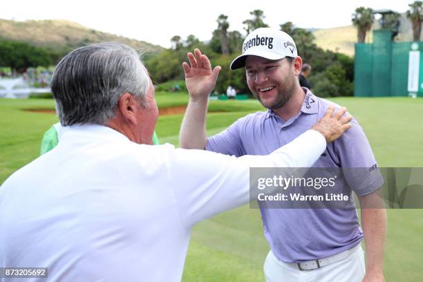 Branden Grace of South Africa is congratulated by Gary Player on the 18th green during the final round of the Nedbank Golf Challenge at Gary Player...